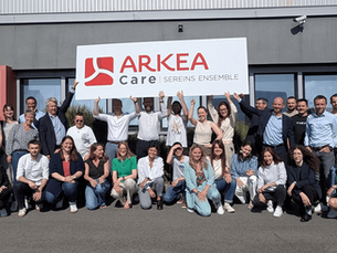 Toute l'équipe d'Arkéa Assistance et Arkéa Creative Care qui tient un panneau Arkéa Care avec la signature : Sereins ensemble